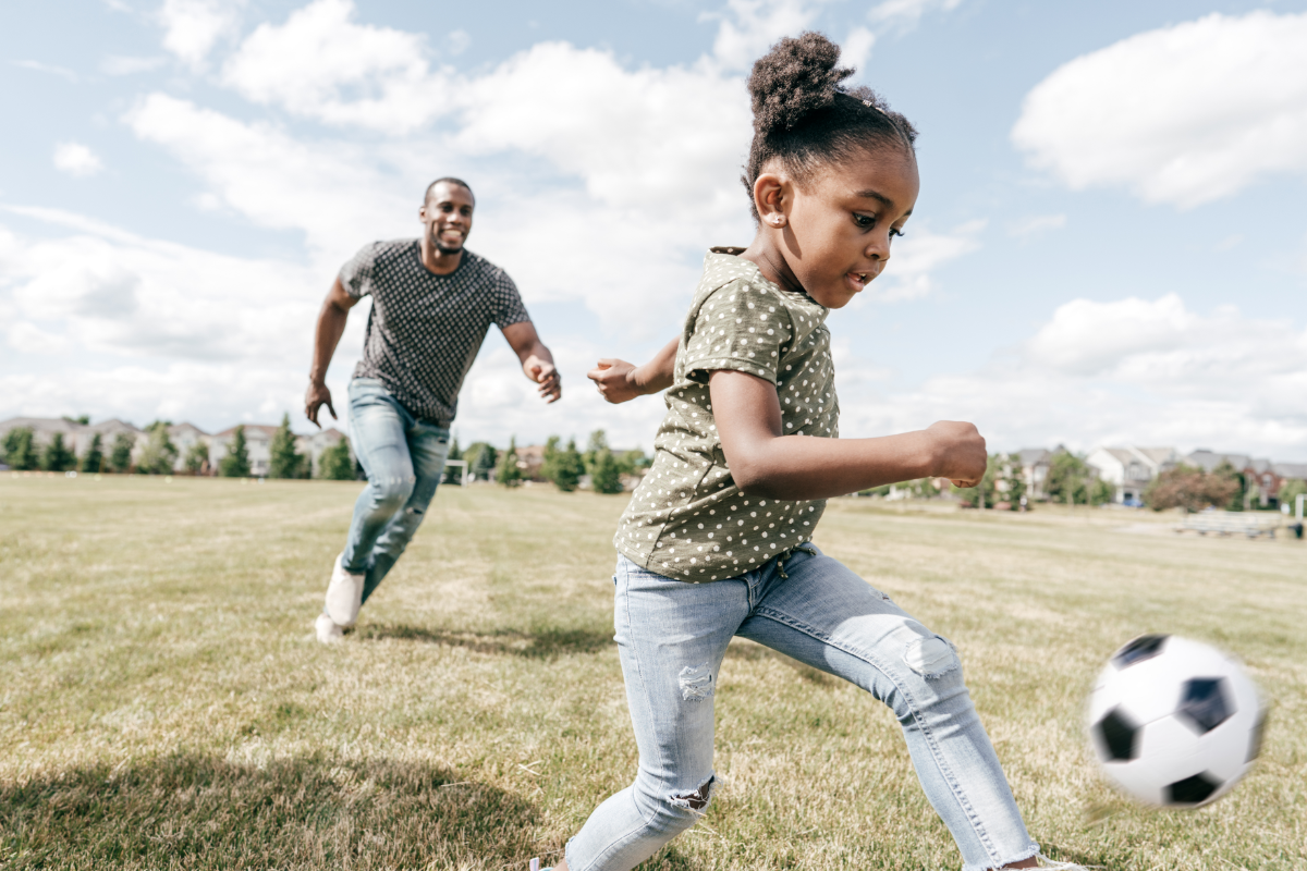 Youth Soccer girl dribbling a ball with her dad