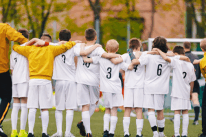 Youth Soccer team locking arms while cheering on their teammate