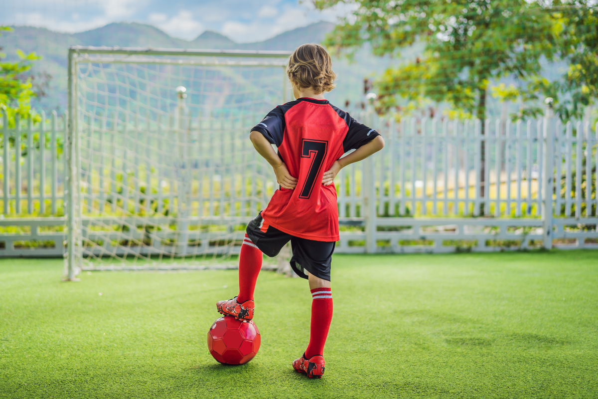 youth soccer player with number seven standing on a ball