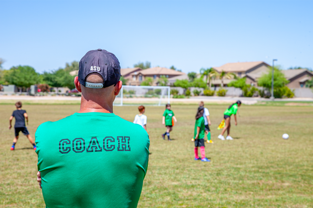 coach watching his team practice while handling the opposing sideline youth soccer